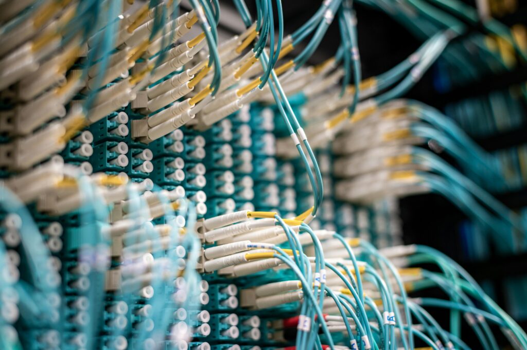 pexels-photo-4864249-4864249 Detailed image of blue fiber optic cables in a data center with equipment connections.